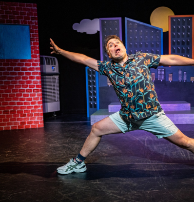 M. John Kennedy stars in Fireside Munsch - pictured on stage in a goofy stance with a goofy expression