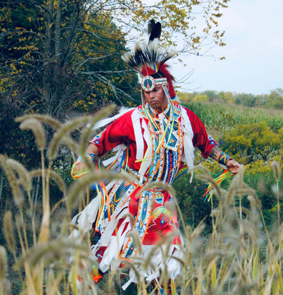Derek Martin from Tribal Vision Dance - dancing in a field wearing traditional regalia