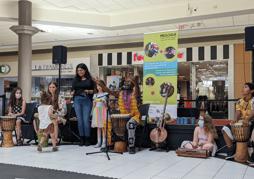 Njacko Backo performs on stage at Eglinton Square with young audience members