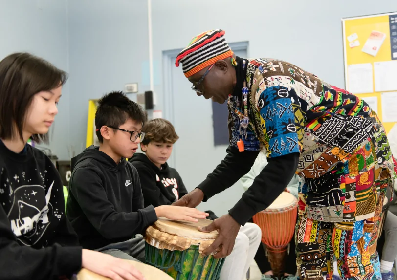 Njacko Backo running a percussion workshop - showing a student proper hand placement