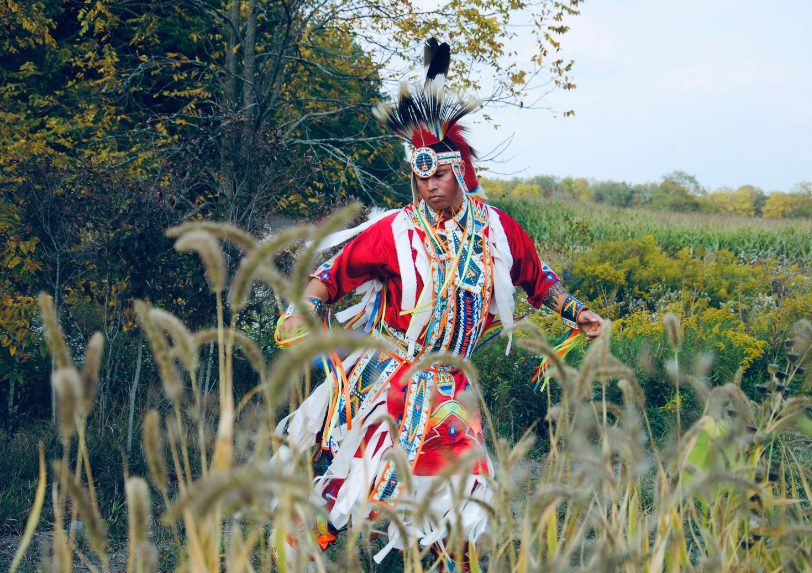 Derek Martin from Tribal Vision Dance dances in a field wearing traditional regalia