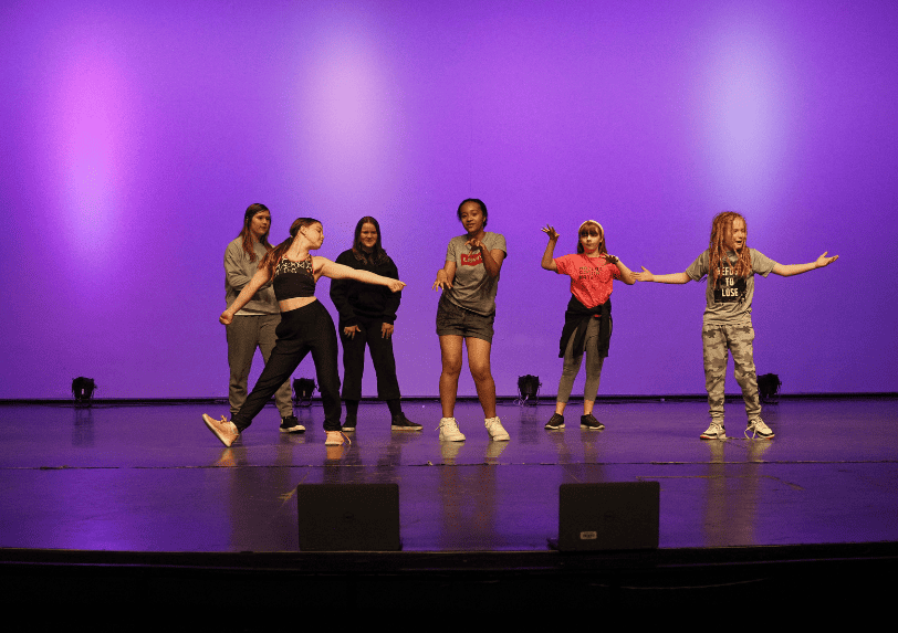 Students dance on stage while participating in the leadership through the arts program