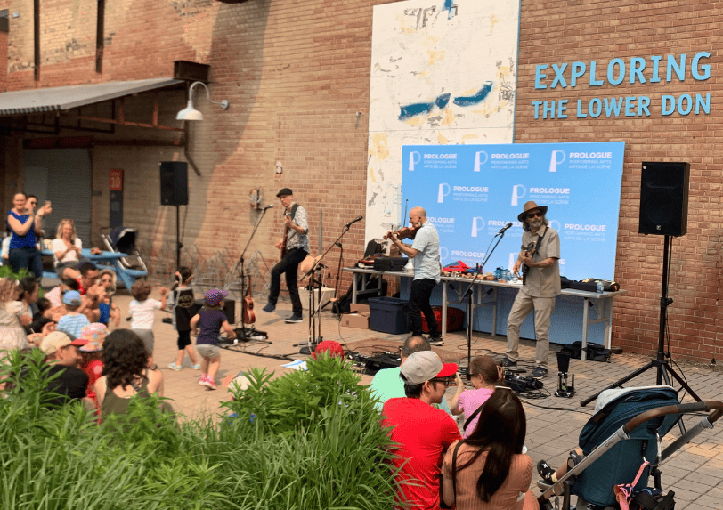Sultans of String performing at Arts Break at Brick Works surrounded by a crowd of families