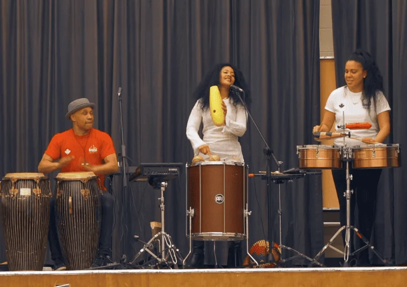 Joaquin Nunez and Rumberos play on stage at a school